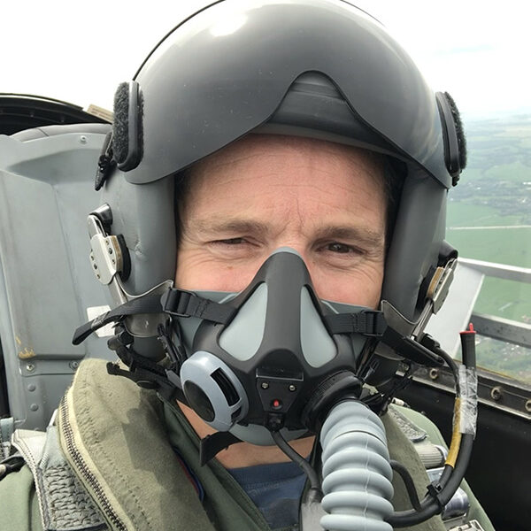Fighter pilot wearing helmet inside cockpit, calm expression and controlled focus