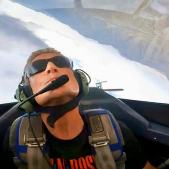 Fighter pilot wearing helmet inside cockpit, calm expression and controlled focus.”